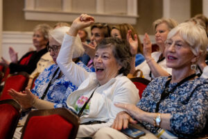 Alums cheer, with one raising her hand up, during the Alumni Achievement Award ceremony inside Smith Hall Theatre 