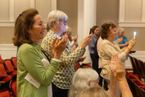 Alums stand and clap inside Smith Hall Theatre during during the Alumni Achievement Award ceremony