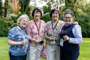 A group of alums pose for a photo together outside of Randolph House