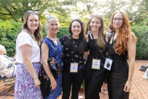 A group of alums pose for a photo together outside of Randolph House