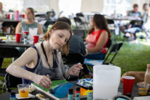 A woman is painting on a table with other people at a table.