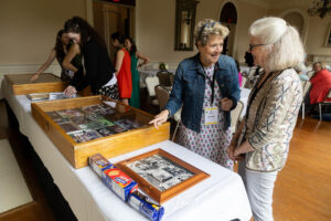 Two women standing near a table with pictures on it.