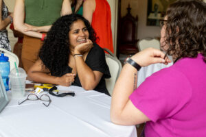 Two women sitting at a table talking to each other.