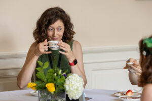 A woman sitting at a table with a cup of tea.