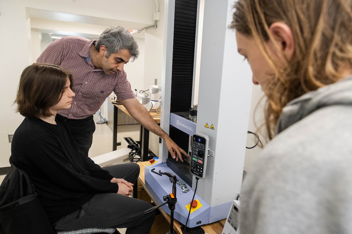 A professor and two students are working with a 3D printer