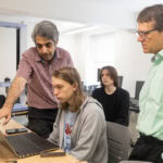 Two professors and two students looking at a laptop. Two professors and two students looking at a laptop.