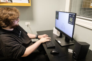 A man sitting at a desk with a computer and keyboard.