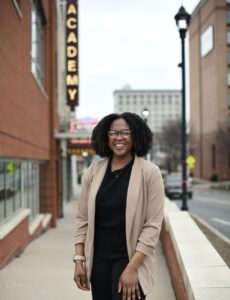 A woman stands in front of a marquee, posing for a photo