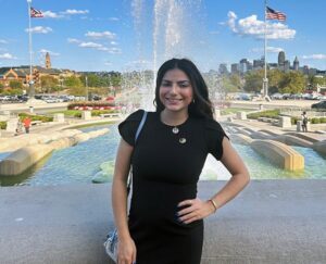 A woman in a black dress standing next to a fountain.