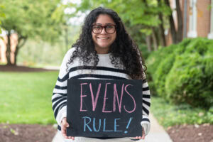 A student holds a chalkboard that says "EVENS RULE"