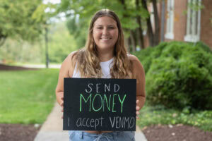 Student poses with a chalkboard that says "Send Money. I Accept Venmo." 