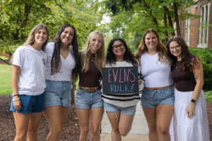 A group of students pose with a chalkboard that says "Evens Rule"