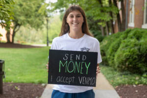 A student poses with a chalkboard that says "send money. i accept venmo."