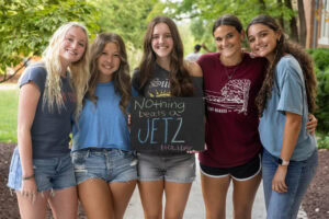 A group of students pose together holding chalkboards with funny sayings on them
