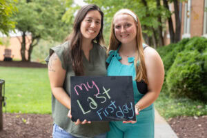 Two students pose with a chalkboard that says "The Life of a WildCat"