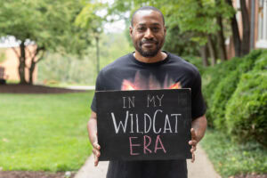 A student poses with a chalkbaord that says "In My WildCat Era"