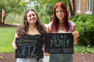 Two students pose together holding chalkboards with funny sayings on them