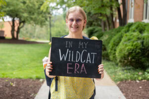 A student poses with a chalkboard that says "In My WildCat Era" 