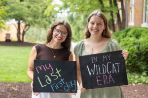 Two students pose together holding chalkboards with funny sayings on them