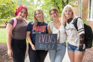A group of students pose with a sign that says "Evens Rule"