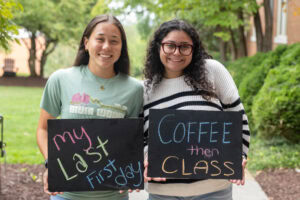 Two students pose together holding chalkboards with funny sayings on them