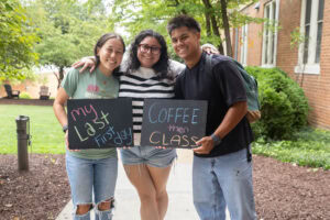 A group of students pose together holding chalkboards with funny sayings on them