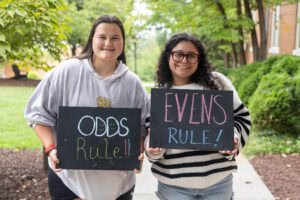 Two students pose together holding chalkboards with funny sayings on them