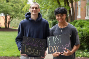 Two students pose together holding chalkboards with funny sayings on them