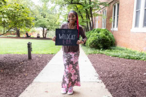 A student poses with a chalkboard that says "In My WildCat Era"