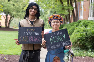 Two students pose together holding chalkboards with funny sayings on them