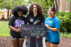 A group of students pose together holding chalkboards with funny sayings on them