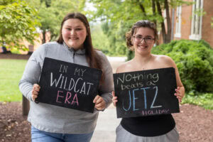 Two students pose together holding chalkboards with funny sayings on them