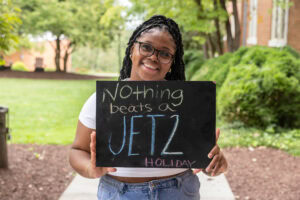 A student poses with a chalkboard that says "Nothing beats a Jet2 holiday" 