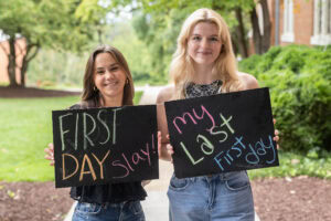 Two students pose together holding chalkboards with funny sayings on them