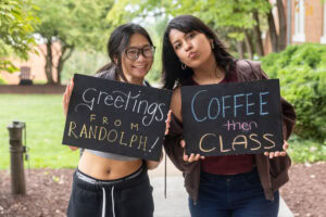 Two students pose together holding chalkboards with funny sayings on them
