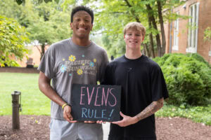 Student pose together with a sign that says "Evens Rule"