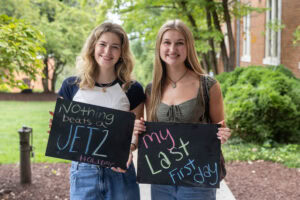 Two students pose together holding chalkboards with funny sayings on them