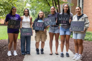 A group of students pose together holding chalkboards with funny sayings on them