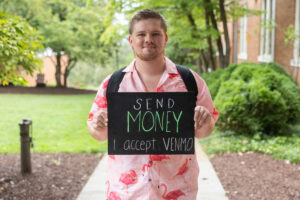 A student poses with a chalkboard that says "send money. i accept venmo."