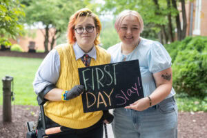 Two students pose with a chalkboard that says "First Day Slay"