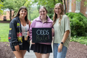 A group of students pose with a sign that says "Odds Rule"