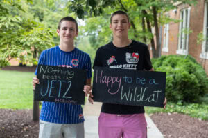 Two students pose together holding chalkboards with funny sayings on them
