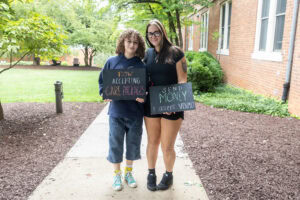 Two students pose together holding chalkboards with funny sayings on them
