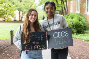 Two students pose together holding chalkboards with funny sayings on them