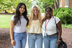 Three students pose for a photo together outside 