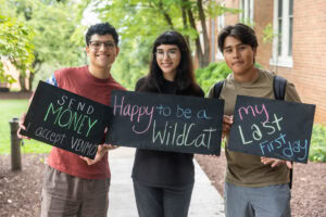 A group of students pose together holding chalkboards with funny sayings on them