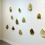 A wall with several gold leafed leaves hanging on it.