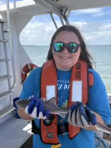 A woman in a life jacket holding a small shark