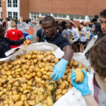 Students take potatoes out of a giant bag of them.