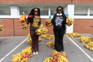 Two students hold up bags of potatoes